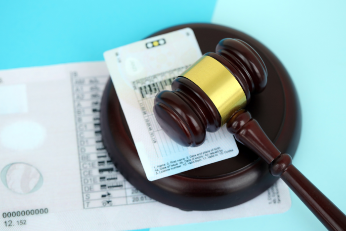 Generic driving license and judgement mallet on blue background close up