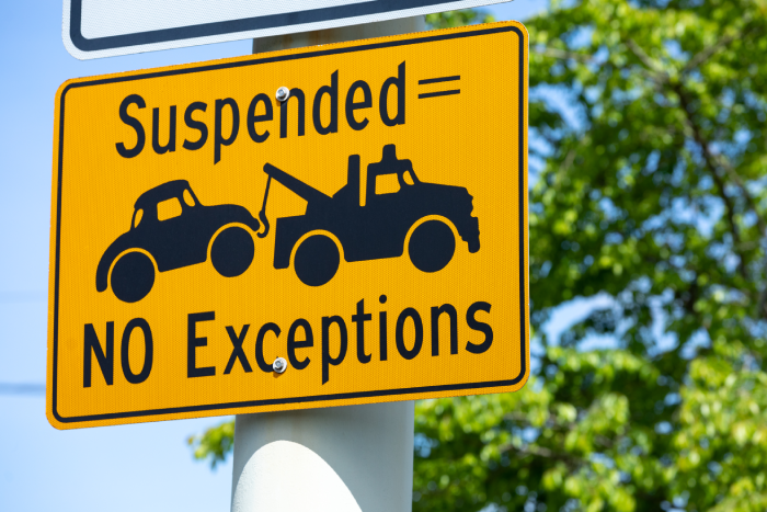Suspended License = Towed Car. No Exception" road signs along a roadway, with space for text on the right