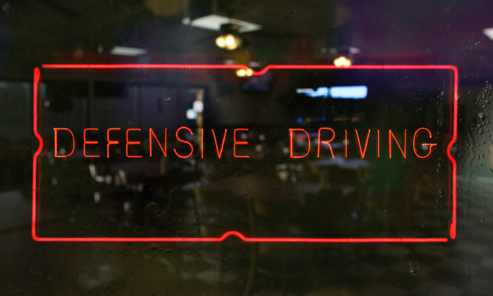 Neon Defensive Driving Sign in Wet Window of Restaurant