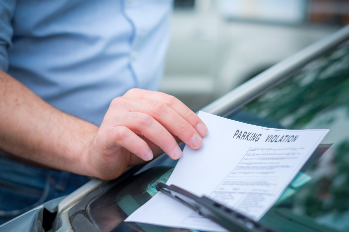 Man finding a ticket fine under the car windscreen because of parking violation