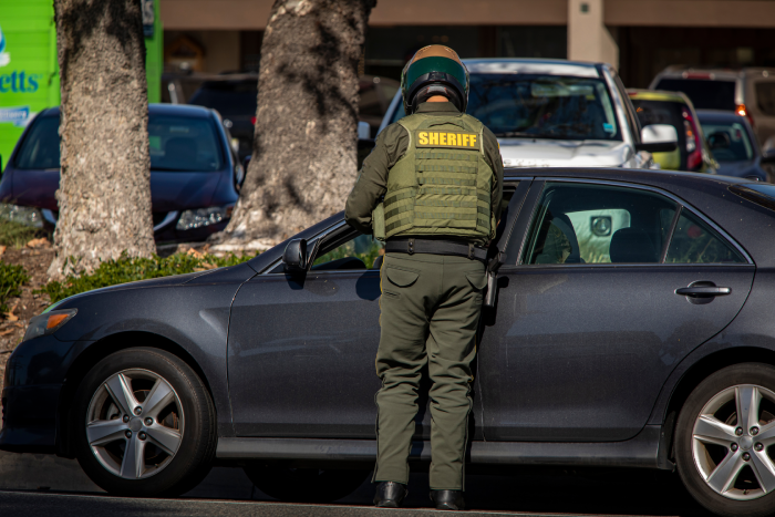Motoycycle police officer giving a traffic ticket to person in sedan type car
