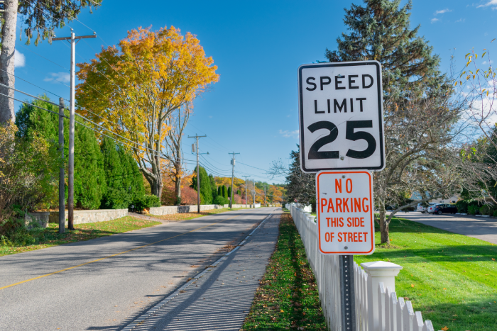 Traditional American speed limit and no parking signs above a white picket fence on Ocean Ave,