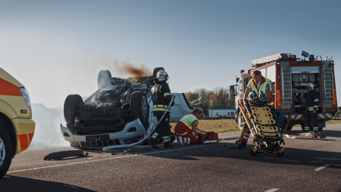On the Car Crash Traffic Accident Scene: Team of Firefighters Rescue Injured People Trapped in Rollover Vehicle.