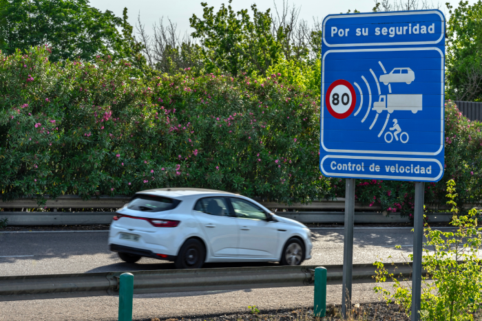 Speed camera warning sign and fast car driving on a road in Spain