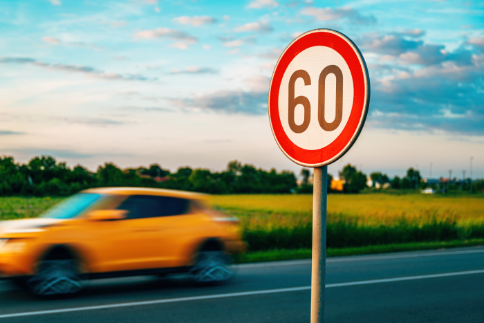 Car speeding by the speed limit traffic sign, motion blur image with selective focus