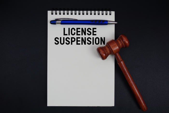 License Suspension text written on notepad with gavel on black background