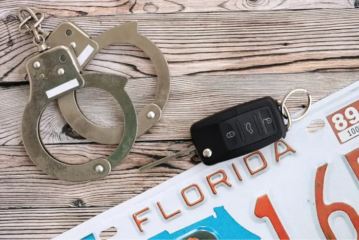 Remote control car keys on Florida license plate and handcuffs. Concept of car accident in Florida.