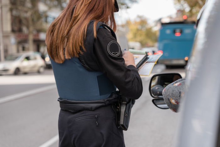 Police officer patrolling the streets and issuing a parking ticket to a car