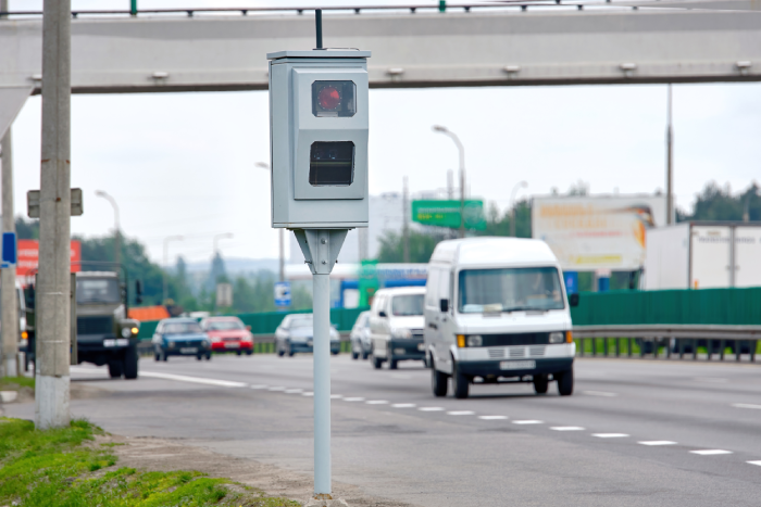 High-tech stationary radar speed camera placed on highway shoulder capturing data of moving vehicles for road law enforcement and traffic monitoring