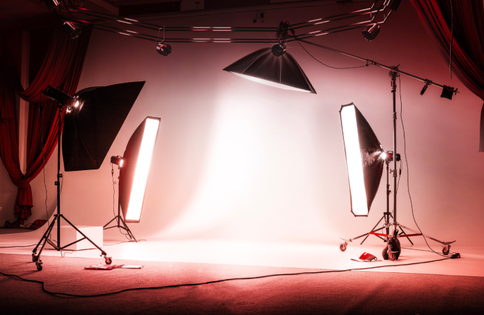 Red photo session studio. Professional sports background for advertisement. Workspace interior with grey backdrop, backstage and lamps