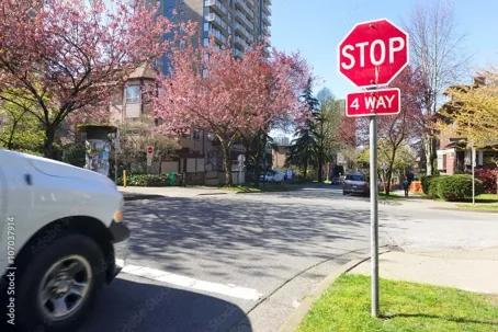 An image of a stopped car with a 4 way stop sign in front of it.