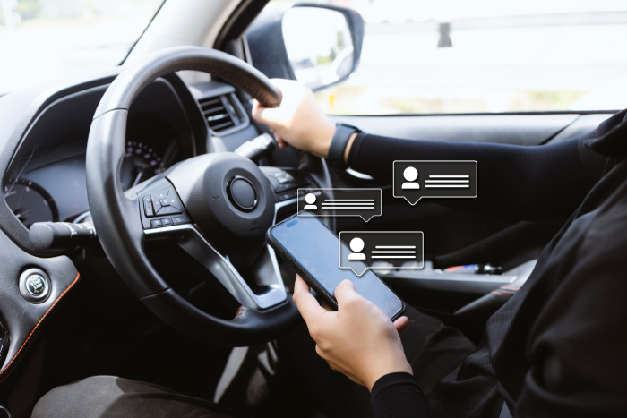 Person texting while driving with social media notifications, symbolizing distracted driving and smartphone addiction risk.
